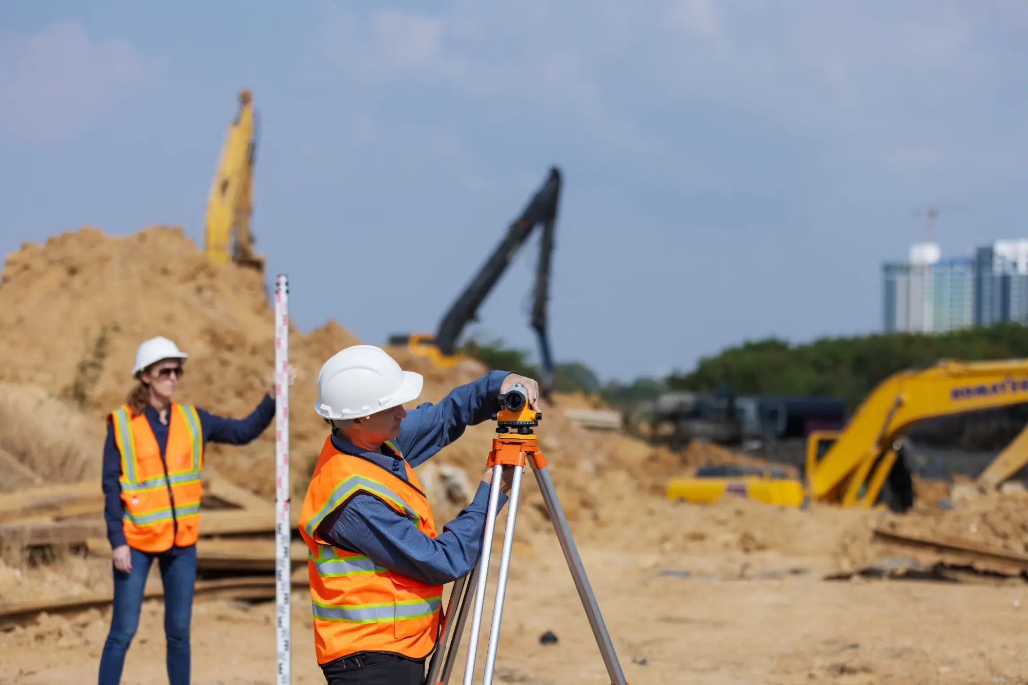 Civil engineers using survey equipment to verify grading and elevation at an active earthwork site