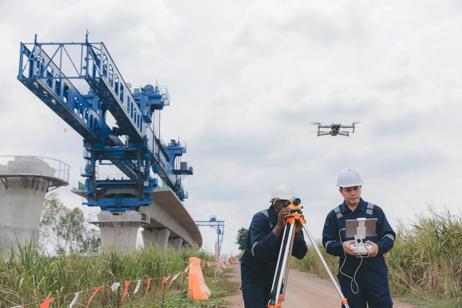 Survey crew combining a total station and UAV drone to capture data at an infrastructure construction site