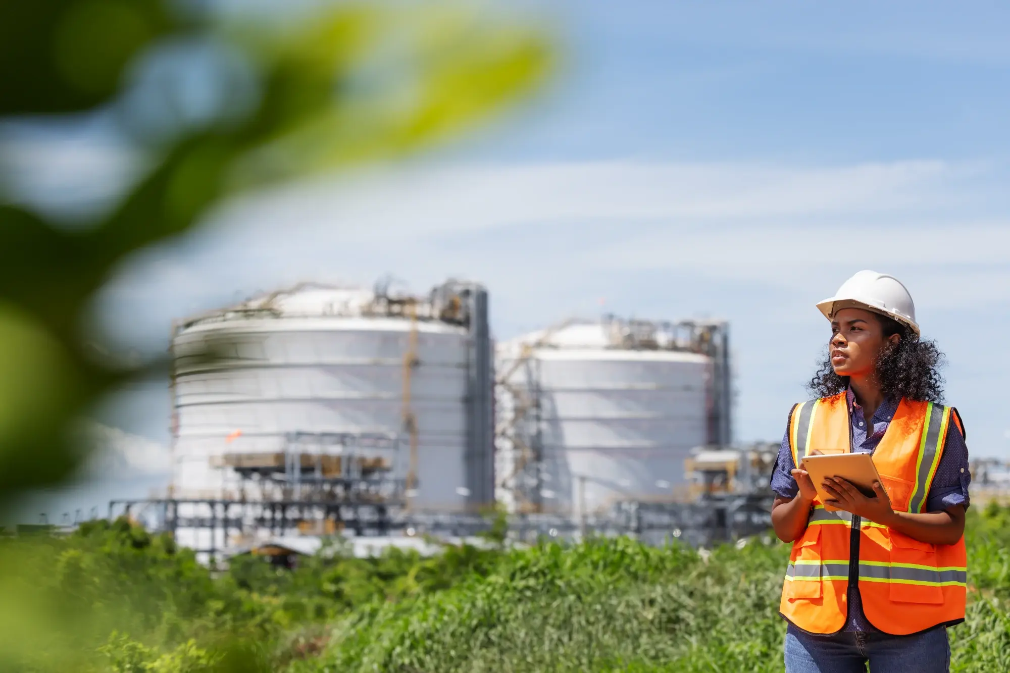 Environmental engineer conducting a field site inspection near industrial storage tanks in West Texas