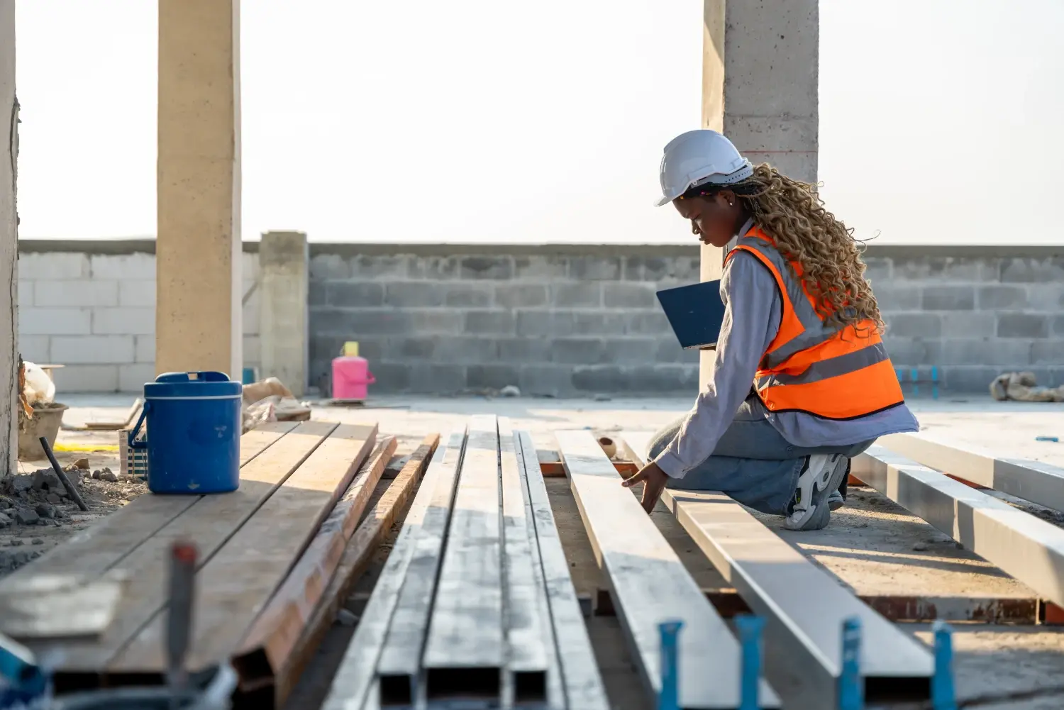 Engineer reviewing steel structural members on-site with a laptop for materials documentation