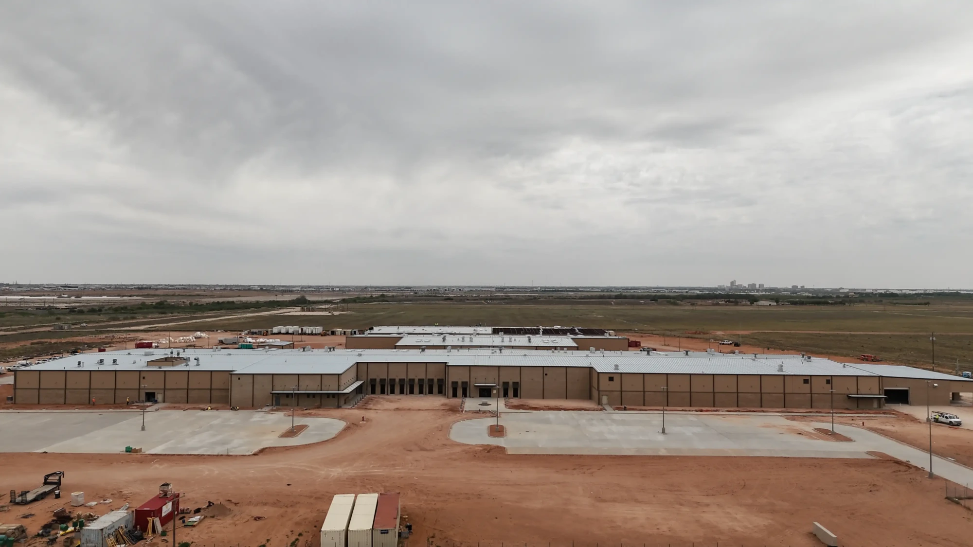 Midland County Detention Facility: The main structure enclosed and roofed, with site paving and parking areas taking shape across the front of the facility.
