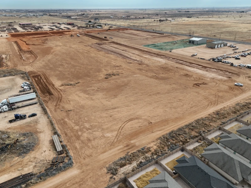 The Nest Subdivision: Mass grading in progress, with drainage features shaped and existing homes along the southern edge.